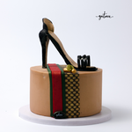 Elegant cake featuring a black high heel shoe atop a box, styled like gucci-shoes-on-a-box