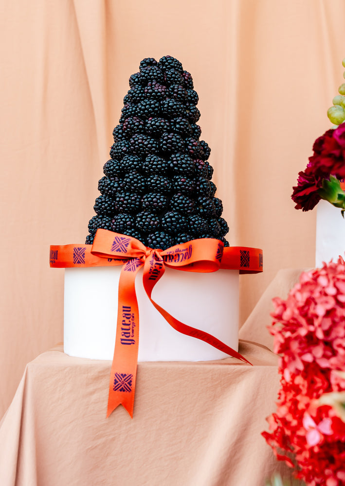 Guilt free fruit dessert featuring a towering blackberry cake adorned with a decorative orange ribbon