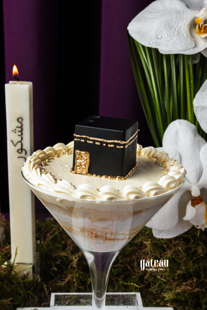Hajj celebration cake by Gateau Gourmet Cafe featuring a black Kaaba design on creamy white frosting