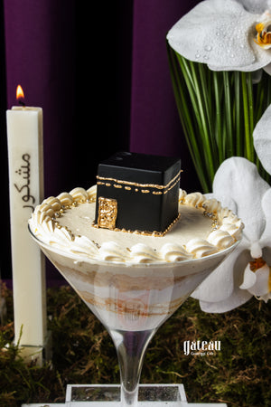 Hajj celebration cake by Gateau Gourmet Cafe featuring a black Kaaba design on creamy white frosting
