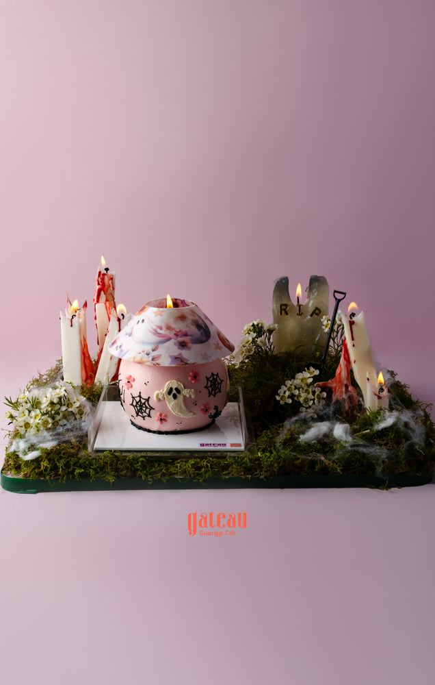 Halloween celebration cake with decorations featuring spooky elements like candles and a gravestone