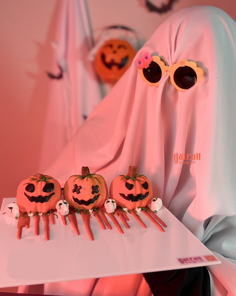 Halloween-themed pumpkin mousse cake spice decorated with faces and ghost toppings on a white platter