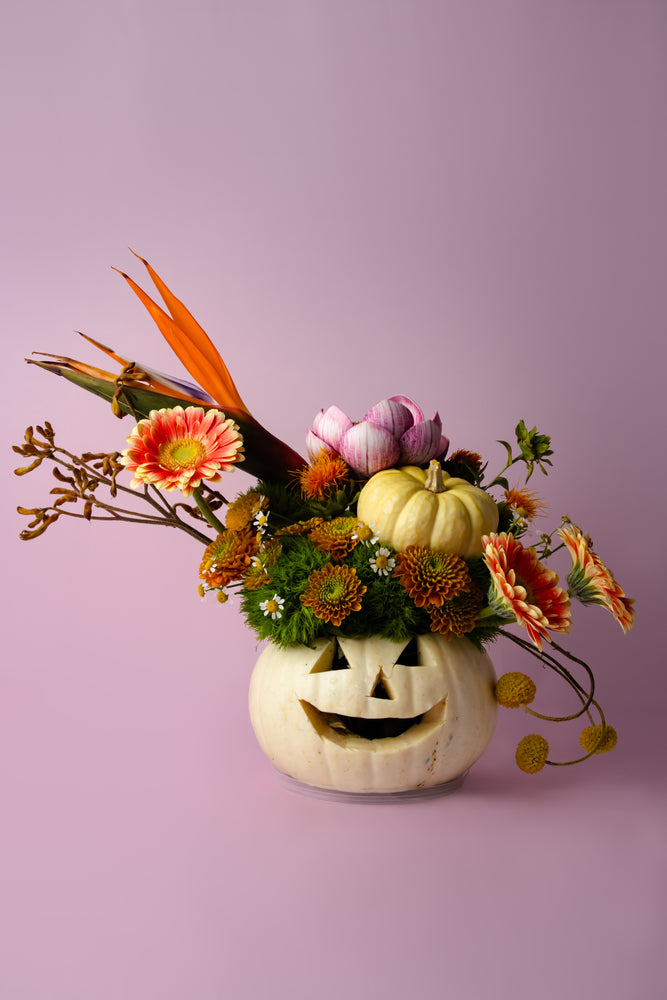 Halloween pumpkin vase with flowers featuring vibrant blooms and a smiling jack-o'-lantern design