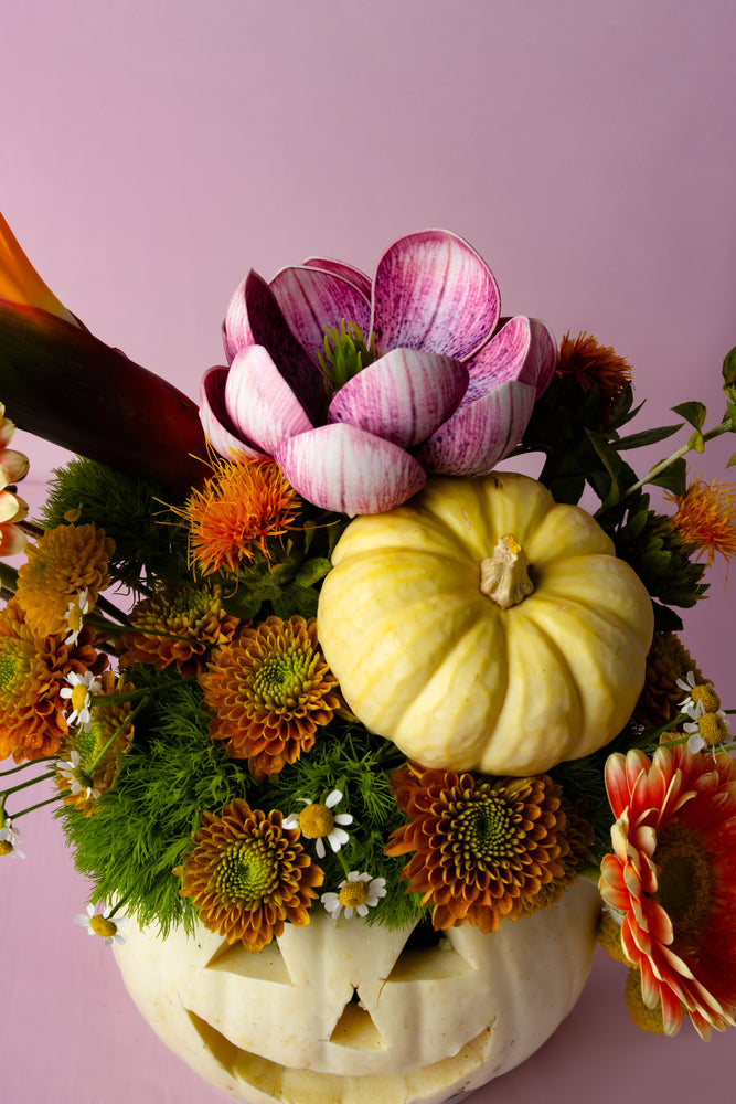 Halloween pumpkin vase with flowers, featuring colorful blooms and a carved pumpkin design
