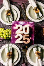Holiday cake displaying 2025 surrounded by festive table setting with stylish plates and holiday baking gifts