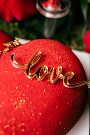 Love Mousse Cake With Arrangement featuring a red sparkly surface and a gold 'love' decoration on top