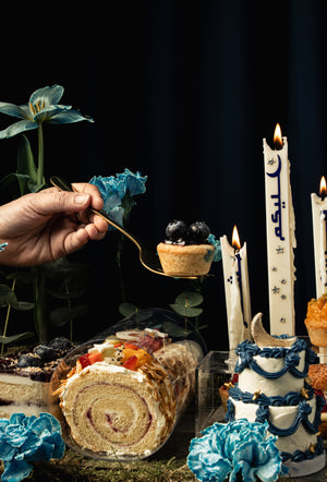 Gateau Gourmet Cafe Ramadan dessert tray featuring assorted cakes and decorative candles with blue floral accents