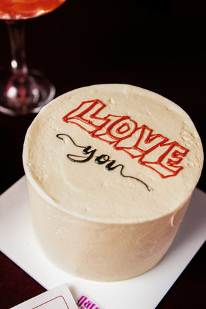 Mini Love White Cake With Candle decorated with red lettering saying Love You