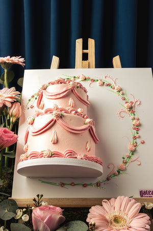 Pink tiered Mother's Day cake with floral decorations and elegant frosting by Gateau Gourmet Cafe