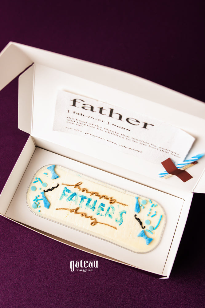 Father's Day loaf cake from Gateau Gourmet Cafe decorated with blue and brown icing in a white gift box