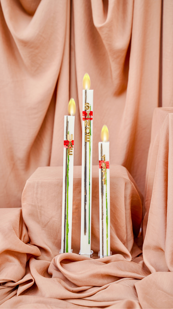 Three elegant National Day candles with flame-like tips, beautifully arranged on soft fabric