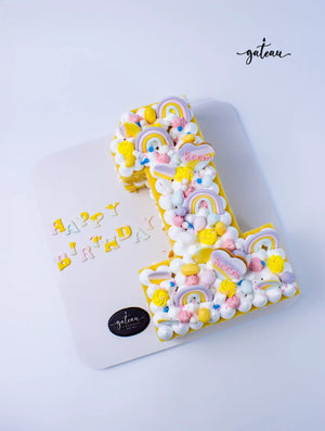 Number shaped birthday cake decorated with pastel rainbows and colorful frosting from Gateau Gourmet Cafe