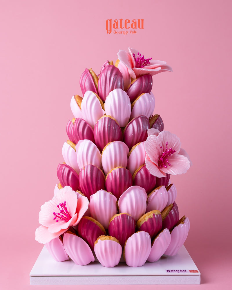 Stunning pink madeleine cake centerpiece with layers of pastel-colored cakes and decorative flowers