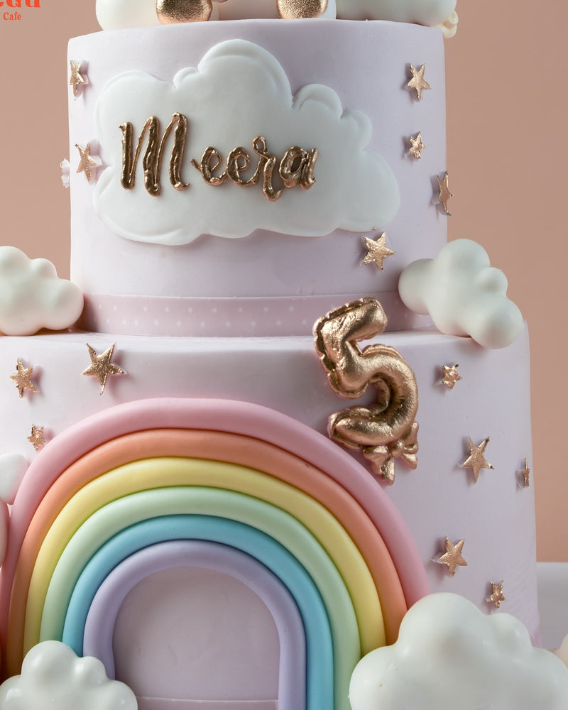 Festive rainbow theme cake design with pastel colors, clouds, and star decorations for a birthday celebration