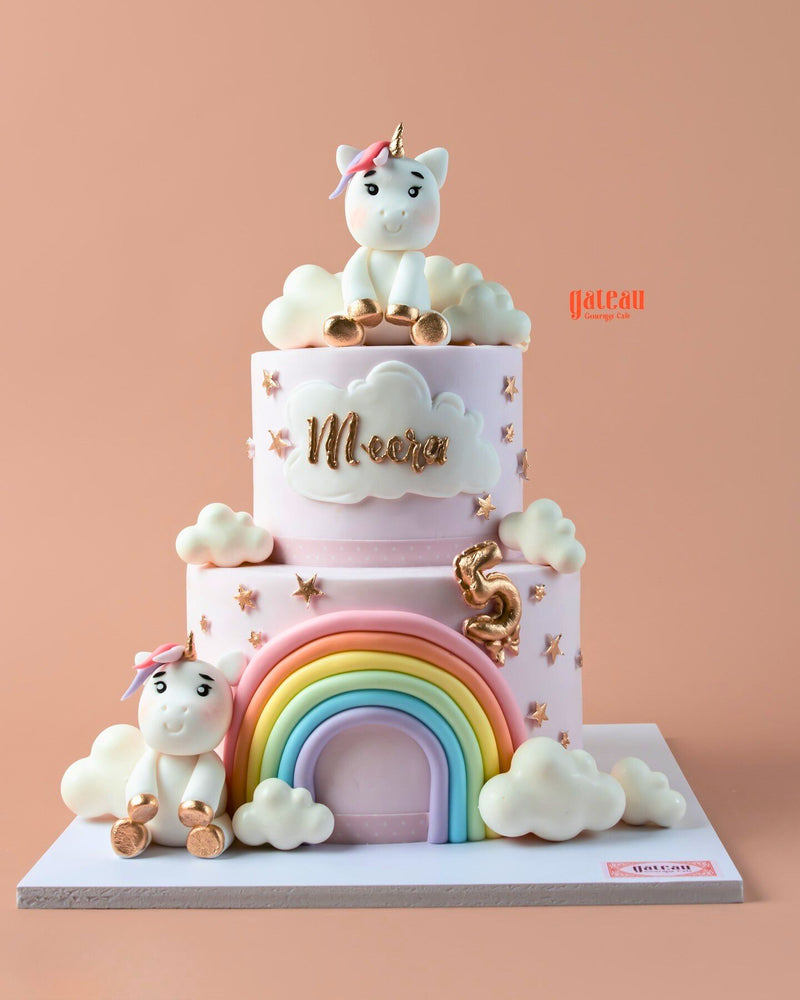 Whimsical rainbow theme cake design with unicorn figures and colorful decorations for celebrations