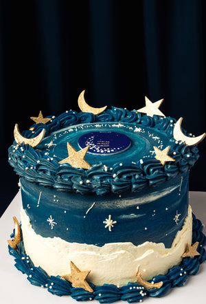 Ramadan celebration cake by Gateau Gourmet Cafe with blue and white frosting decorated with golden stars and crescent moons