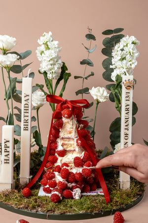Raspberry mountain centerpiece cake decorated with flowers and candles for a special occasion