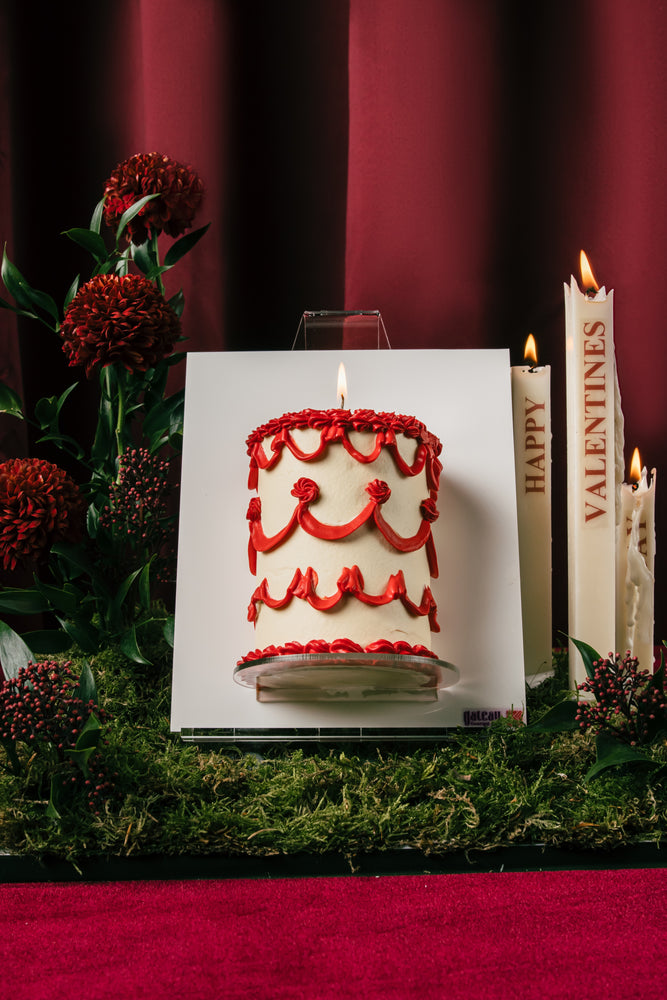 Gateau Gourmet Cafe red shimmer canvas cake with red decorative icing on white frosting displayed with red flowers and candles