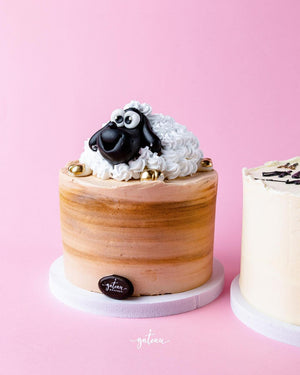 Cute sheep themed cake with fluffy frosting and decorative sheep figure on top