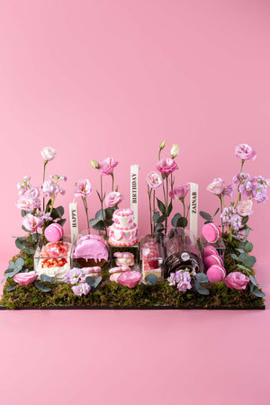 Gateau Gourmet Cafe signature mixed pastries delivery with pink macarons, cake, and flowers on a moss base