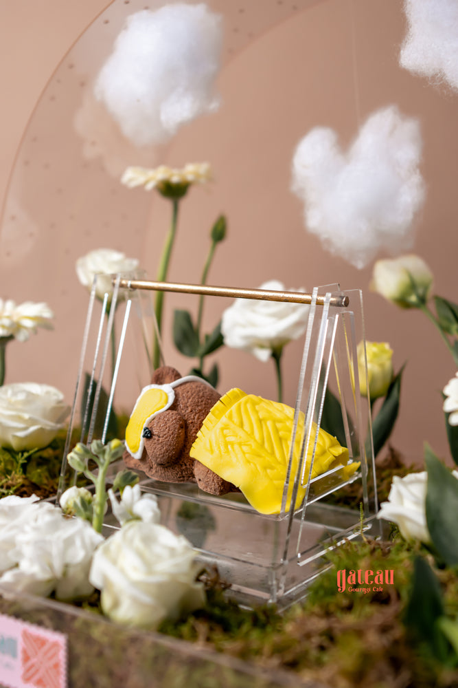 Sleeping bear cake arrangement featuring a plush bear and floral decor from Gateau Gourmet Cafe