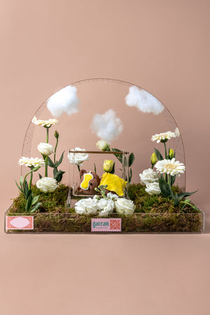 Sleeping bear cake arrangement featuring edible flowers and a charming bear figure on a decorative base