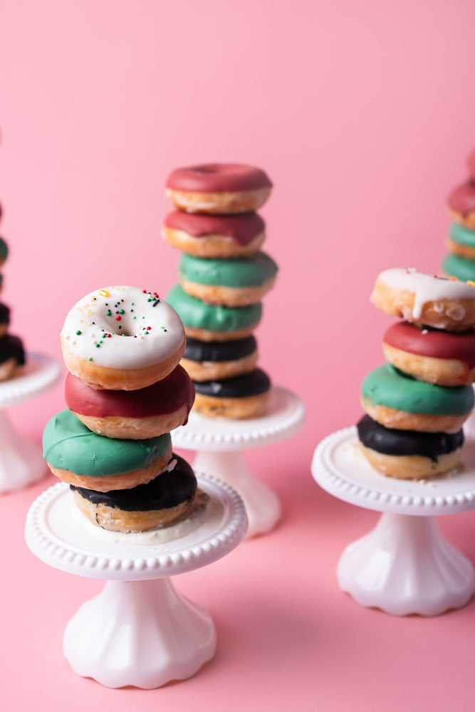 Stack of Gateau Gourmet Cafe specialty flavored donuts on white cake stands with colorful icing