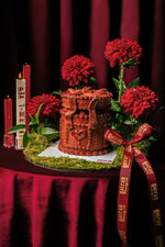 Strawberry Red Box Cake by Gateau Gourmet Cafe decorated with chocolate frosting and surrounded by red flowers and candles