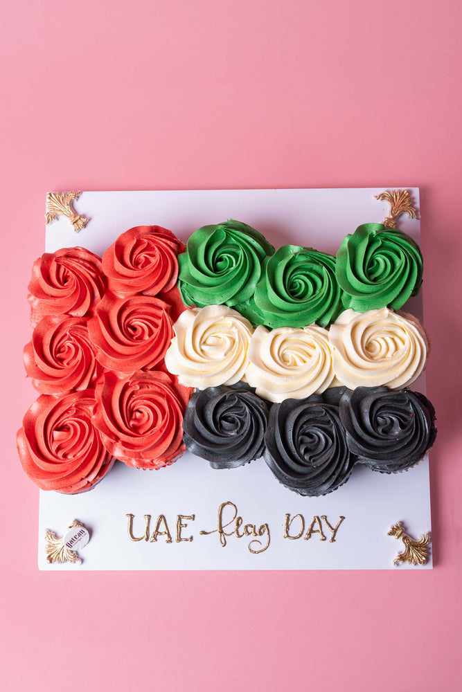 Gateau Gourmet Cafe UAE Flag Day cupcakes arranged in red green white and black frosting swirls on a decorated board