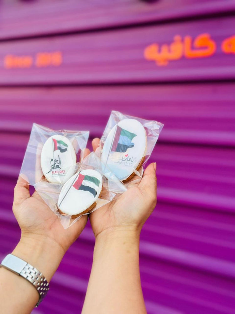 Three UAE National Day cookies decorated with flags and a portrait, packaged attractively for celebration