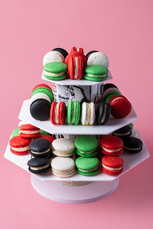 Colorful UAE themed macarons displayed on a tiered stand in red, green, black, and white