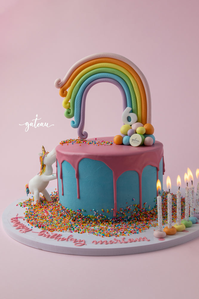 Unicorn Rainbow Cake for birthdays with a colorful rainbow, sprinkles, and decorative candles