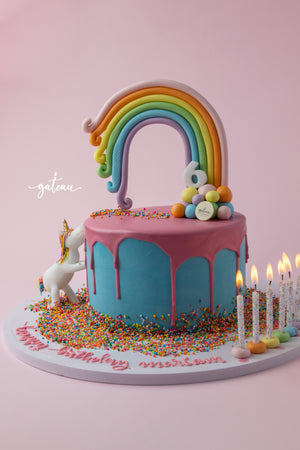 Unicorn Rainbow Cake for birthdays with a colorful rainbow, sprinkles, and decorative candles