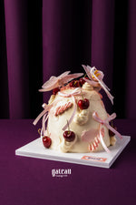 Unique birthday cake with cherries from Gateau Gourmet Cafe decorated with pink ribbons and cream swirls