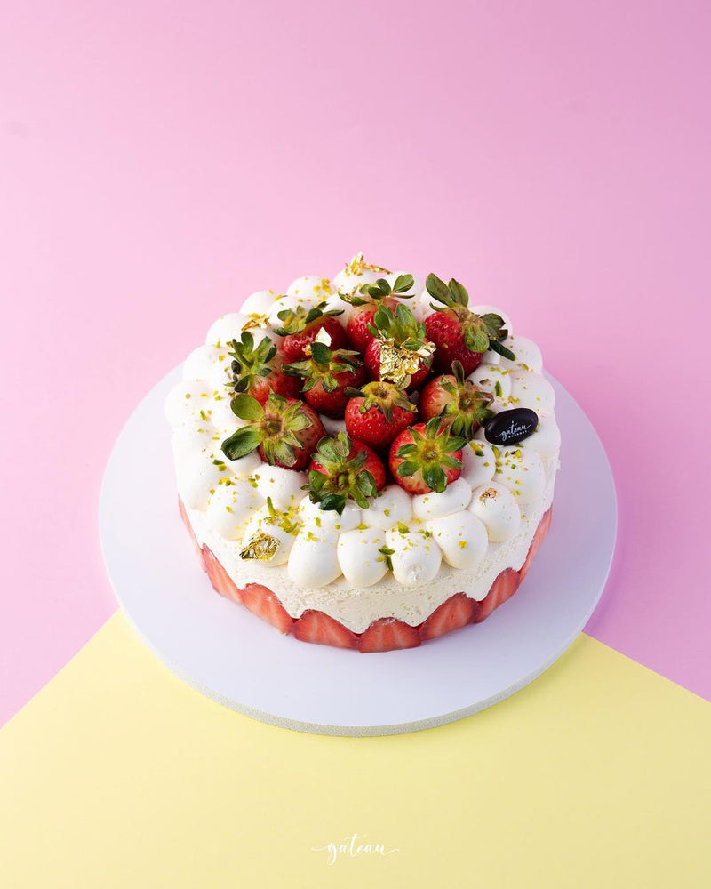 Gateau Gourmet Cafe Vanilla Strawberry Cake topped with fresh strawberries and whipped cream on a white plate
