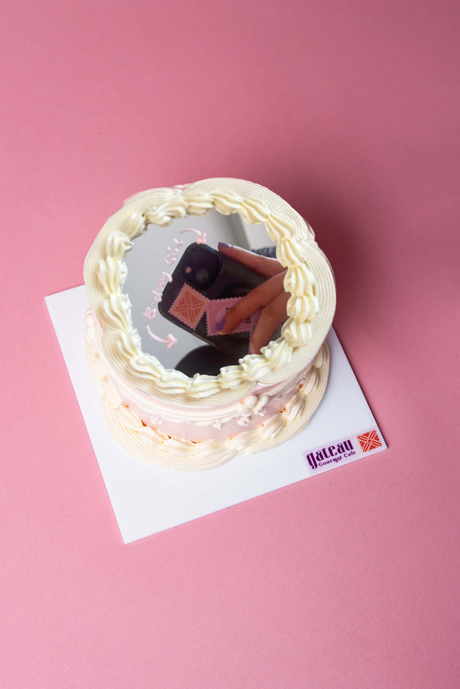 Victorian mirror cake by Gateau Gourmet Cafe with decorative white frosting on a pink background