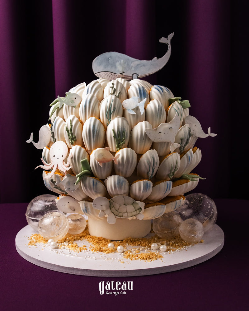 Whale theme madeline tower dessert decorated with white chocolate whales and sea creatures on a cake stand