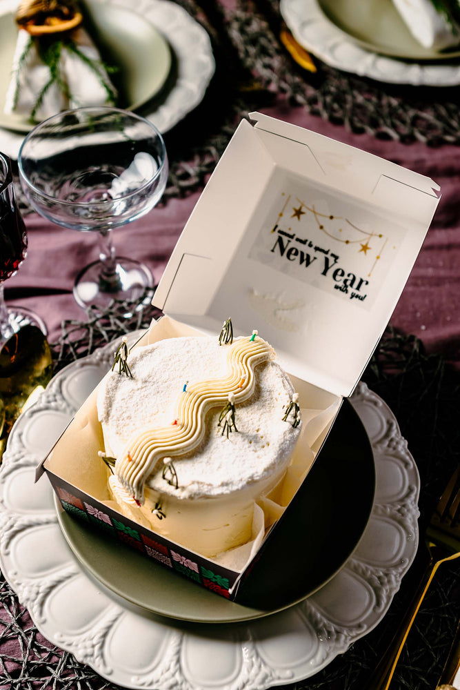 Gateau Gourmet Cafe White Snow Mountain Design Cake in a box on a decorative plate for New Year celebration