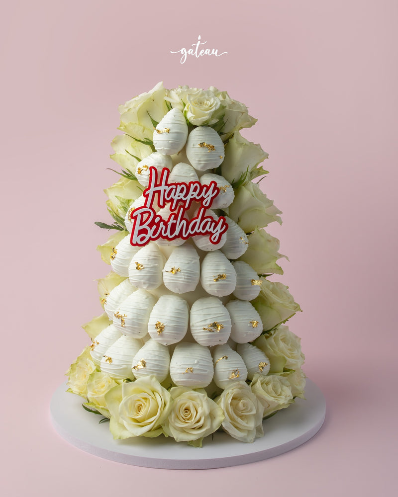 Elegant white strawberry tower cake adorned with roses and a Happy Birthday sign